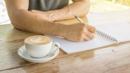 Man writing on a notebook in a cafe.