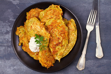 Potato Pancakes. Vegetable fritters. Latkes on black plate. View from above, top studio shot, horizontal
