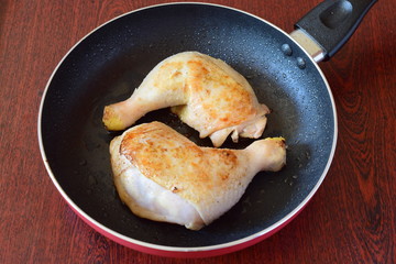 Chicken thighs fried in a frying pan on olive oil