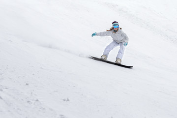 Young woman snowboarder in motion on snowboard in mountains
