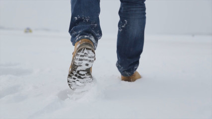 Man walking in snow. Man walking on snow, footprints in snow, behind. Man walks in the winter in the field