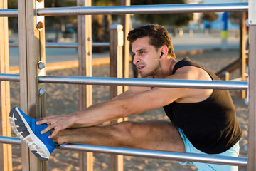 Fototapeta na wymiar Male athlete stretching on outdoor fitness station