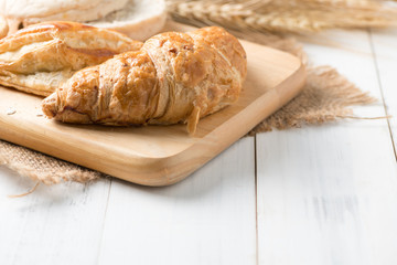Homemade croissant on wood block and white wood