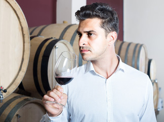 portrait of  man tasting wine sample in glass in alcohol section with woods