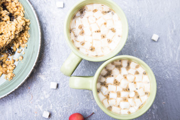 Two cup of hot coffee or chocolate and grated cake with marshmallow on grey background. Flat lay marshmallow. Top view.