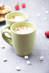 Two cup of hot coffee or chocolate and cake with marshmallow on grey background. Closeup.