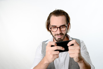 portrait of a 30 years old nerd geek playing game app on a smartphone isolated on white background