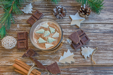 Delicious cup of hot chocolate cocoa with Christmas tree candies on wooden table with  chocolate slices and christmas decoration. Winter holidays drink concept. Top view.