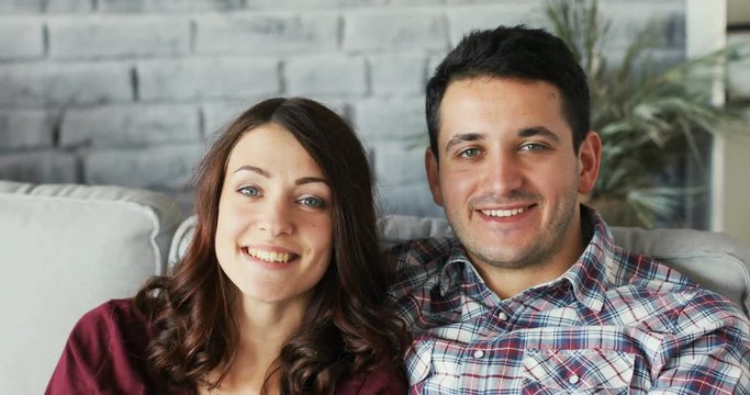 Portrait of young emotional couple in love looking in camera smile feel happy at home on the sofa close up relax relationship hugging and laughting together. Slow Motion Shot on RED EPIC camera