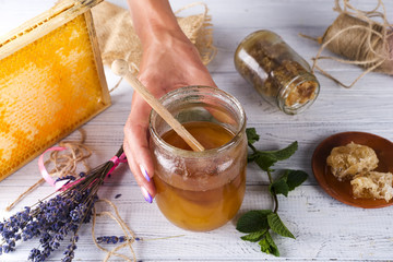women's hands hold a jar of honey