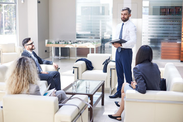 Full length portrait of middle-aged entrepreneur wearing classical suit presenting his point of view concerning topical issue while having working meeting at spacious boardroom