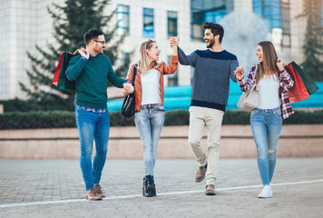 Group Of Friends Walking Along Street With Shopping Bags