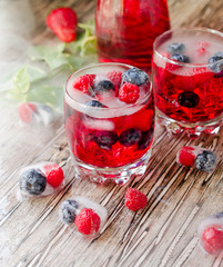 Summer berry lemonade with frozen berries on a wooden rustic table, selective focus