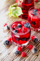Summer berry lemonade with frozen berries on a wooden rustic table, selective focus