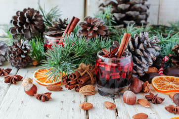 glass of hot mulled wine for the new year with ingredients for cooking, nuts and Christmas...