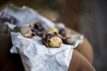 Kastanien abgeschält auf Zeitungspapier am Knie, Querformat