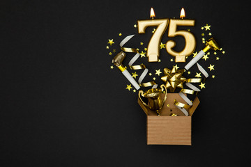 Number 75 gold celebration candle and gift box background