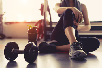 Vrouw oefening training in sportschool fitness breken ontspannen met appel fruit na training sport met halter en eiwit shake fles gezonde levensstijl bodybuilding, atleet bouwer spieren levensstijl.