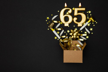 Number 65 gold celebration candle and gift box background
