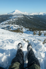 Fototapeta na wymiar legs of the traveler in hiking boots with snow gaiters in the snowy mountains 