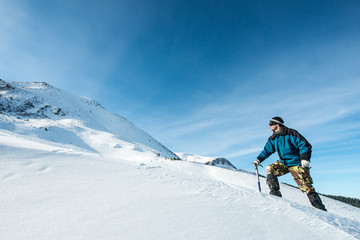 Naklejka na ściany i meble climber with an ice ax in the snowy mountains