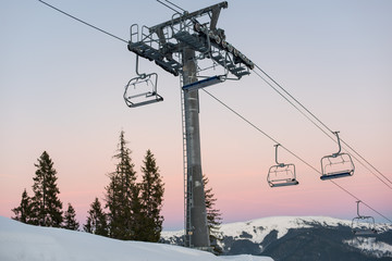 Ski lift chairs on winter resort against a beautiful sky at sunset. Carpathian Mountains, Bukovel, Ukraine