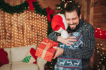 Merry Christmas and Happy New Year!. Young couple celebrating holiday at home. Happy young man and woman hug and give each other gifts