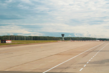 Airport runway with a forest at the background on cloudy day.