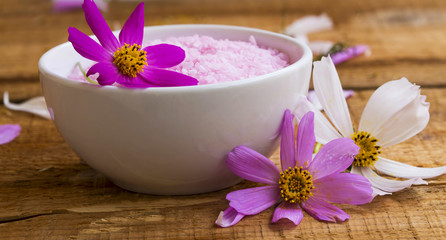 Spa setting with bath salt, floral bath salt bowl on wooden table, wellness and spa concept