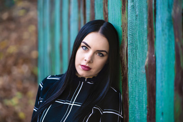 Fototapeta premium Picture with a beautiful brunette in the autumn forest near to a wooden house