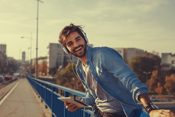 Young man listens to music via a digital tablet in the city