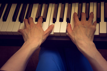 women's hands playing the piano on a dark background
