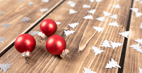 red christmas balls on a wooden background with confetti trees