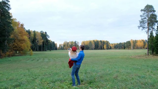Young couple makes a selfie in your modern smartphone and spinning in autumn Park