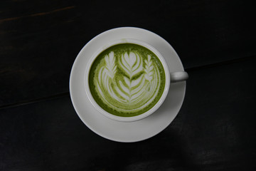 matcha green tea in a white cup on black wooden background, top view