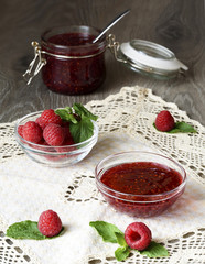 Raspberry jam in a glass jar with fresh raspberry berries