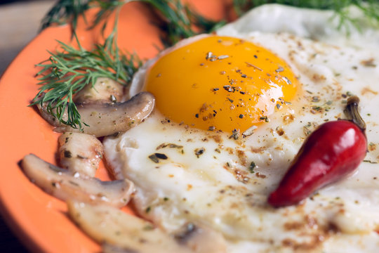 Fried egg with champignons, dill and red chili pepper