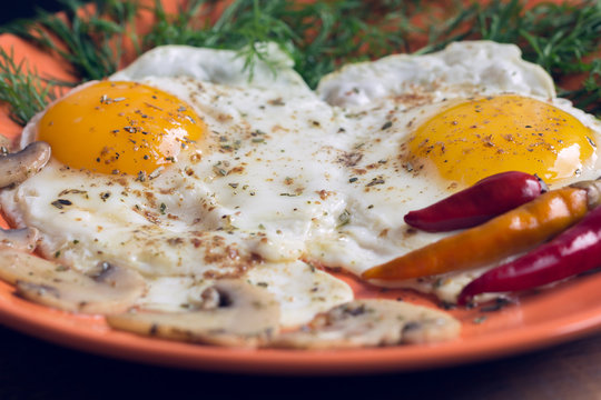 Fried two eggs with champignons, dill and red chili pepper