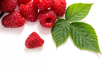 White cup with ripe raspberries and green leaf isolated on white background.