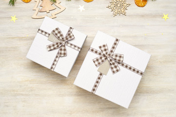 Christmas background. Two gift box with bow of different sizes. Wooden toys in the shape of Christmas trees and snowflakes on a  wooden background