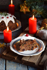 Fototapeta na wymiar Traditional english Christmas steamed pudding with winter berries, dried fruits, nut in festive setting with Xmas tree and burning candle. Fruit cake
