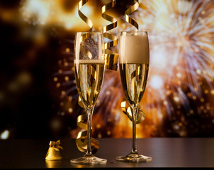 two champagne glasses with ribbons against holiday lights and fireworks - New Year celebrations