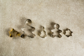 Fototapeta na wymiar Christmas cookie cutters on gray kitchen stone table - christmas tree, gingerbread man, stars. Top view copy space, christmas baking concept