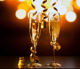 two champagne glasses with ribbons against holiday lights and fireworks - New Year celebrations