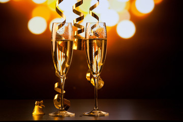 two champagne glasses with ribbons against holiday lights and fireworks - New Year celebrations