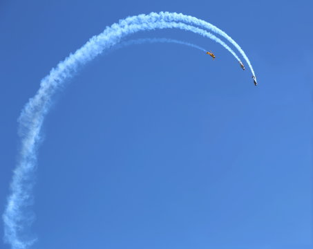 Three planes flying in formation, with smoke trails behind them