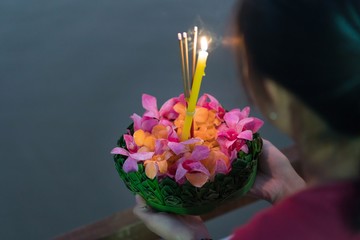 Woman holding decorated float (Krathong) with candles and 
joss sticks are given for Thailand traditional Loy Krathong Festival at the full moon night.