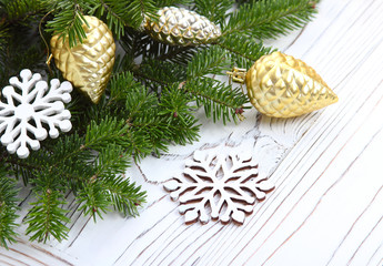 christmas background with green fir branches, golden cones on a white wooden background