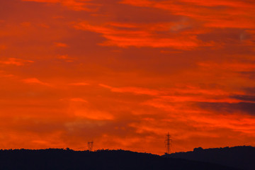 two electricity pylons in sunset red sky