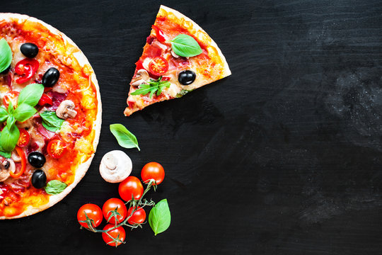 Ham, tomato and cheese  pizza on dark  background. Hot pizza with Pepperoni Sausage served at a pizzeria or restaurant